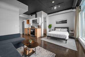 Un apartamento moderno con kitchenette, cama, sofá y zona de comedor.