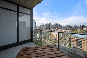 A balcony with a view of a cityscape, including high-rise buildings and a mix of residential and commercial structures.