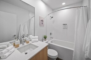 A modern bathroom with a bathtub, toilet, sink, and shower. - Calgary Tower Views | Bright Studio | AC (Calgary)