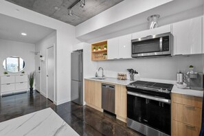 A modern kitchen with stainless steel appliances, wooden cabinets, and a built-in oven. - Calgary Tower Views | Bright Studio | AC (Calgary)