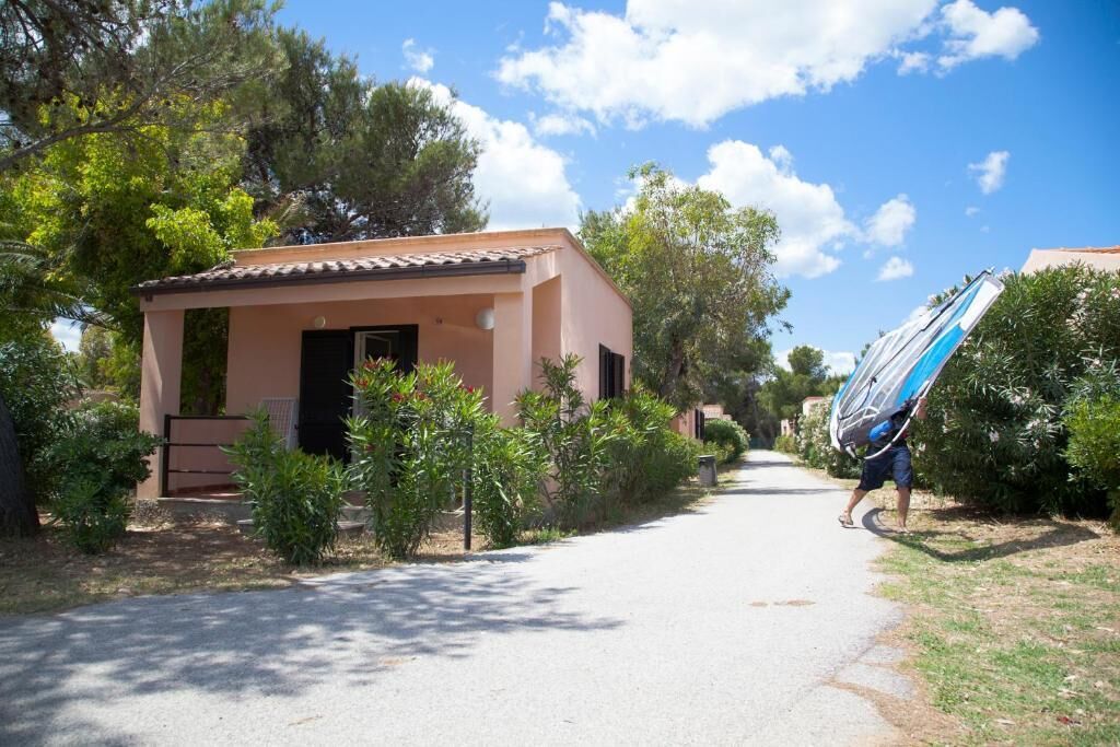 Un chemin mène à un petit bâtiment doté d’un toit en tuiles, entouré de verdure et d’arbres.