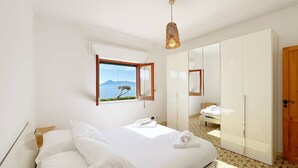 Camera da letto con un letto, una finestra vista, un armadio e una lampada a sospensione.