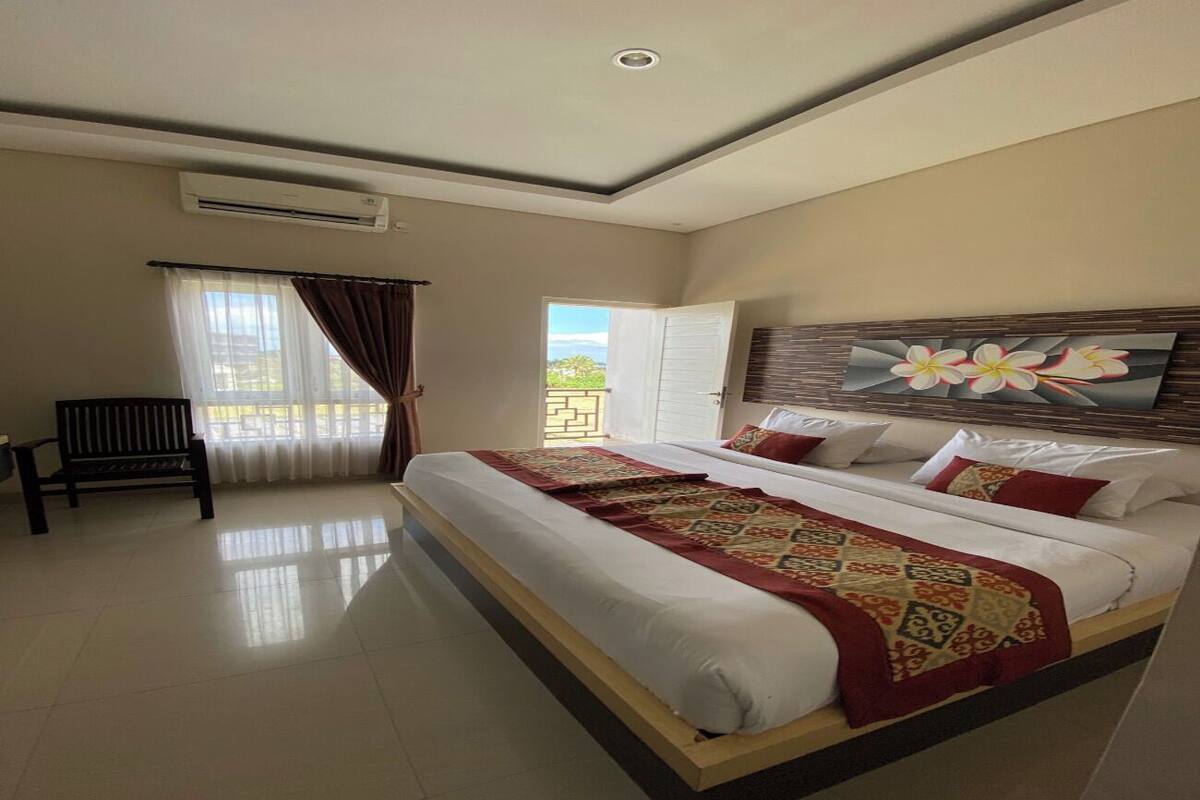 Un dormitorio amplio con una cama grande, un banco y vistas al exterior.