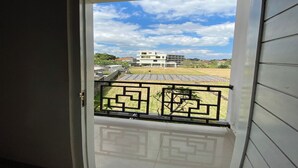 A view from a balcony with a geometric metal railing, a white door, and a building in the background. - Batukaru Garden 5 Bali Sevilla Residence (Tumbak Bayuh)