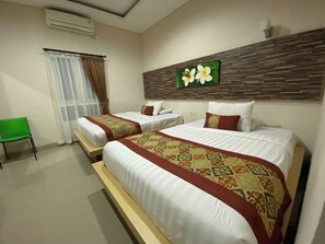 A hotel room with two beds, a green chair, a window with curtains, and a wall-mounted air conditioner. - Batukaru Garden 5 Bali Sevilla Residence (Tumbak Bayuh)