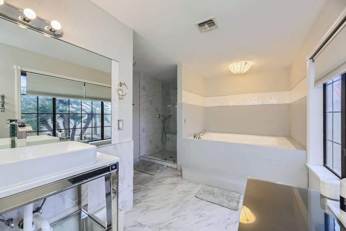 Uma casa de banho moderna com um espelho grande, uma banheira e zona de duche.