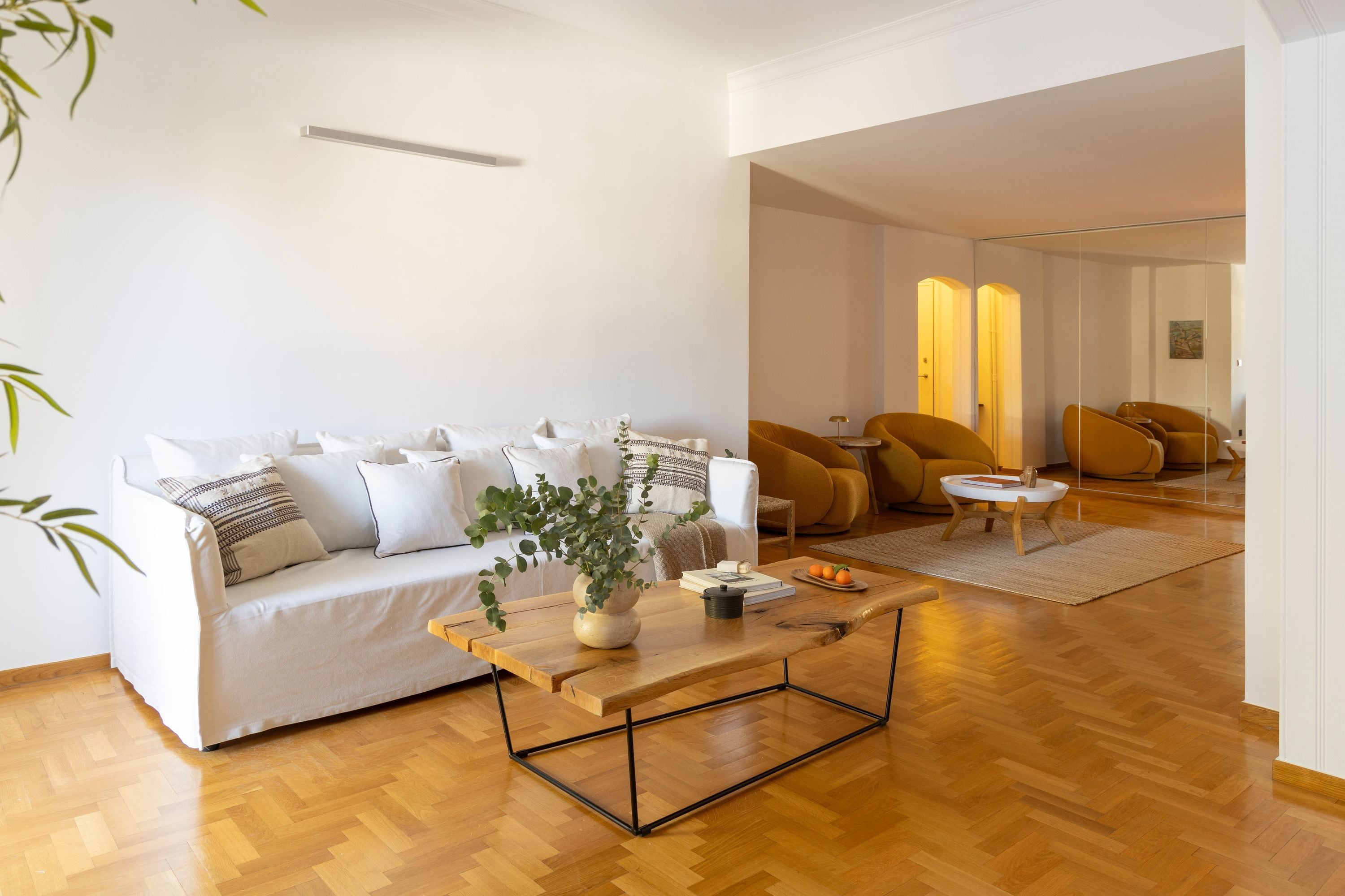 A modern living room with a white sofa, a wooden coffee table, and a plant.