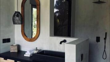 Un baño moderno con tocador negro, espejo con marco de madera y zona de ducha.