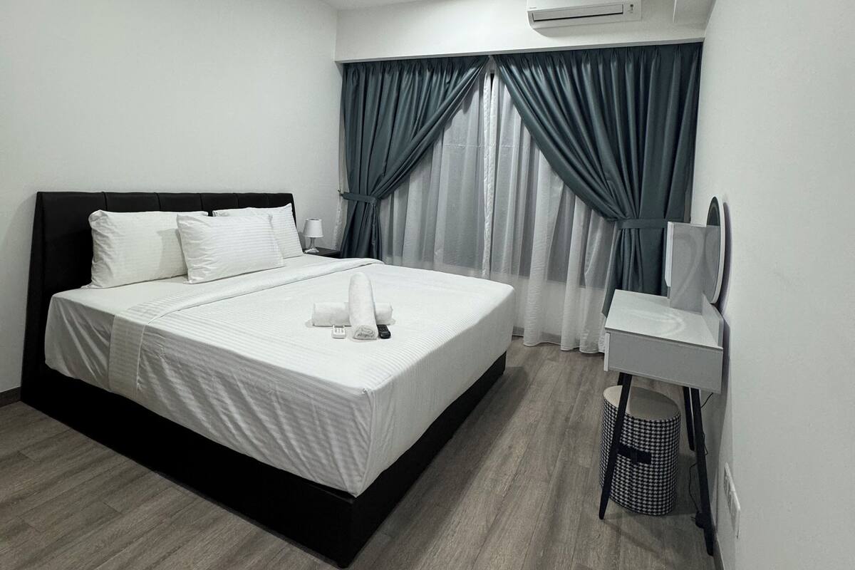 A modern hotel room with a large bed, a bedside table, a mirror, a ceiling fan, and an air conditioning unit.
