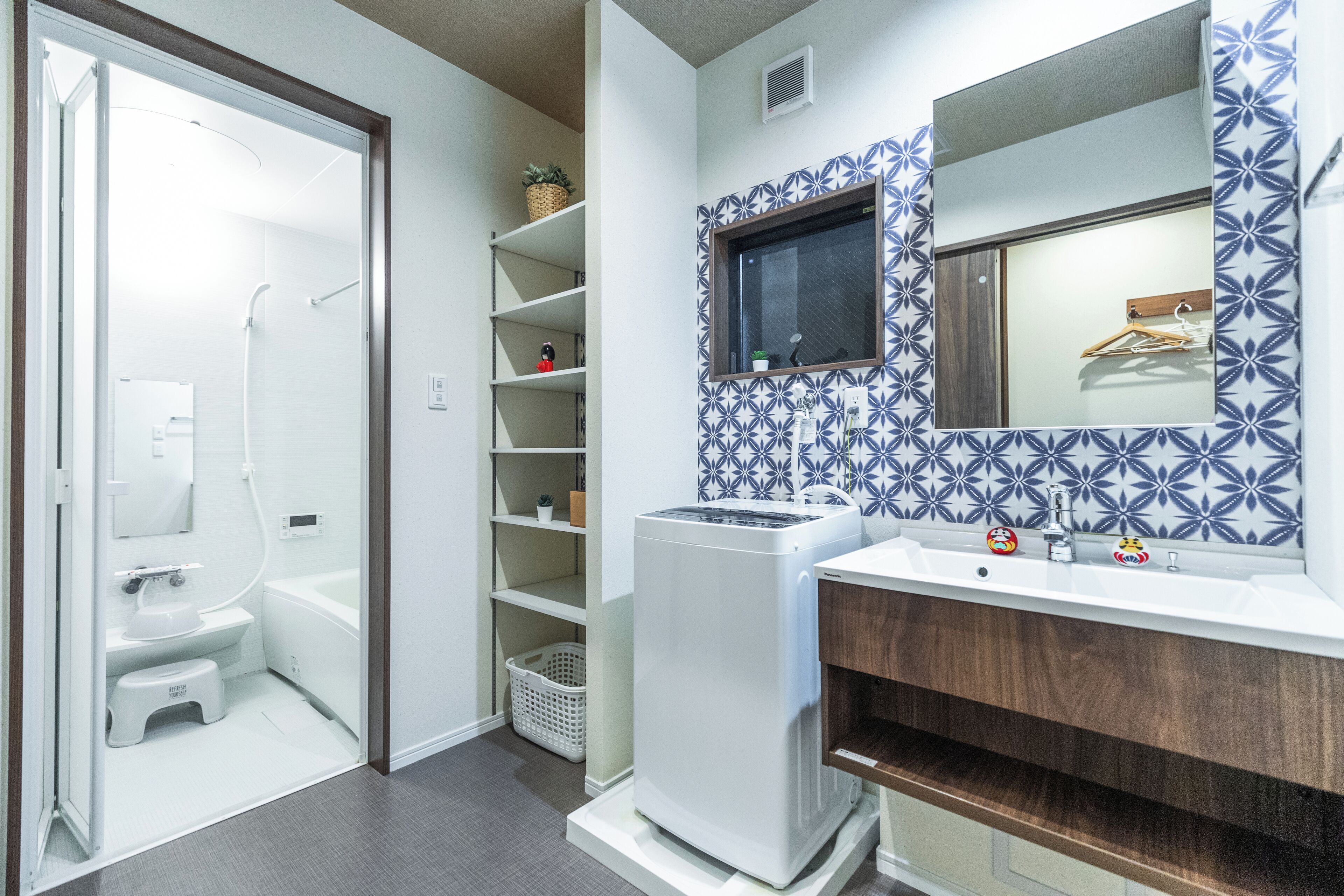 A compact bathroom with a toilet, shower, and a built-in washing machine.