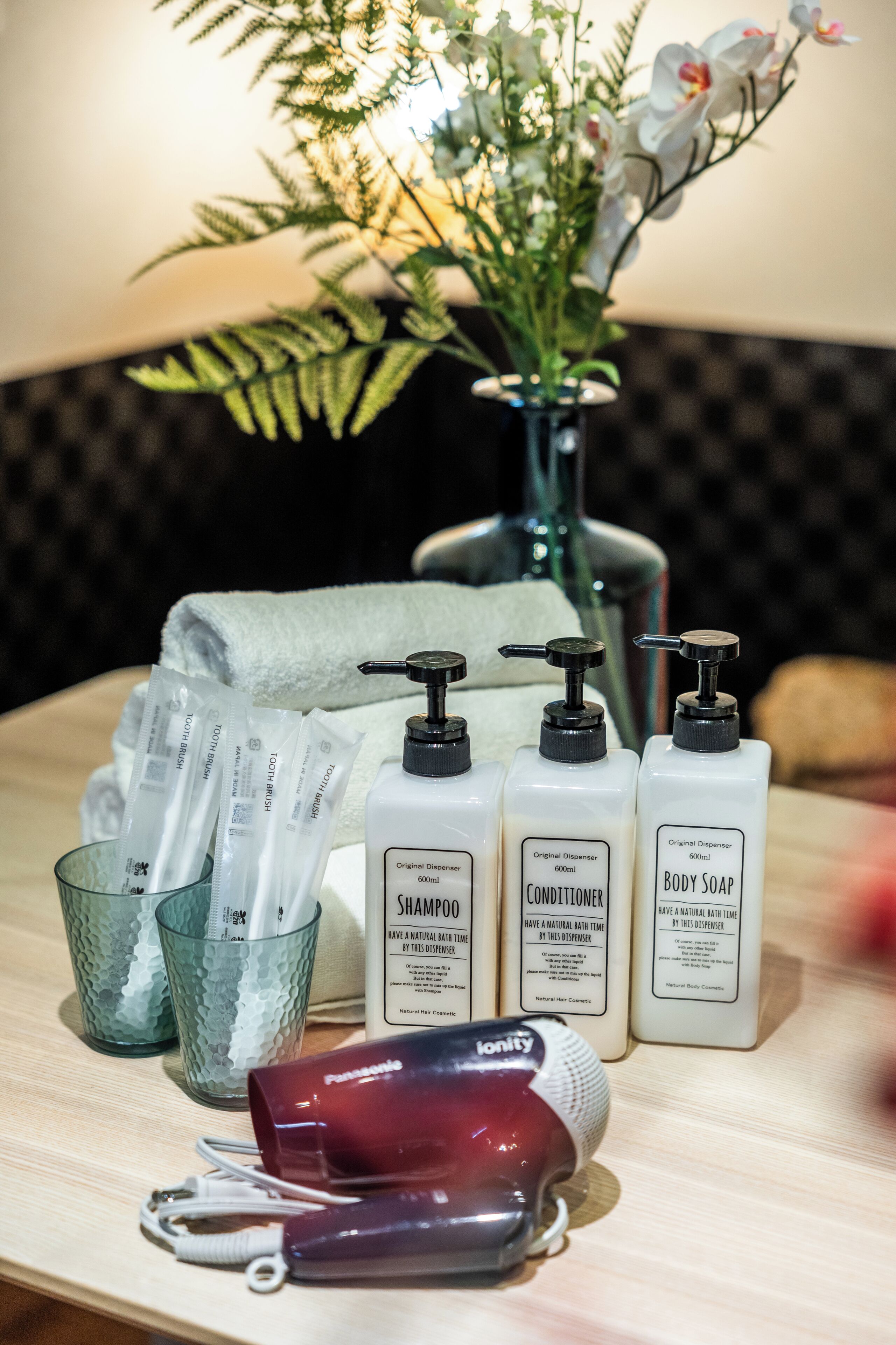 A bathroom vanity with toiletries including shampoo, conditioner, and body soap.
