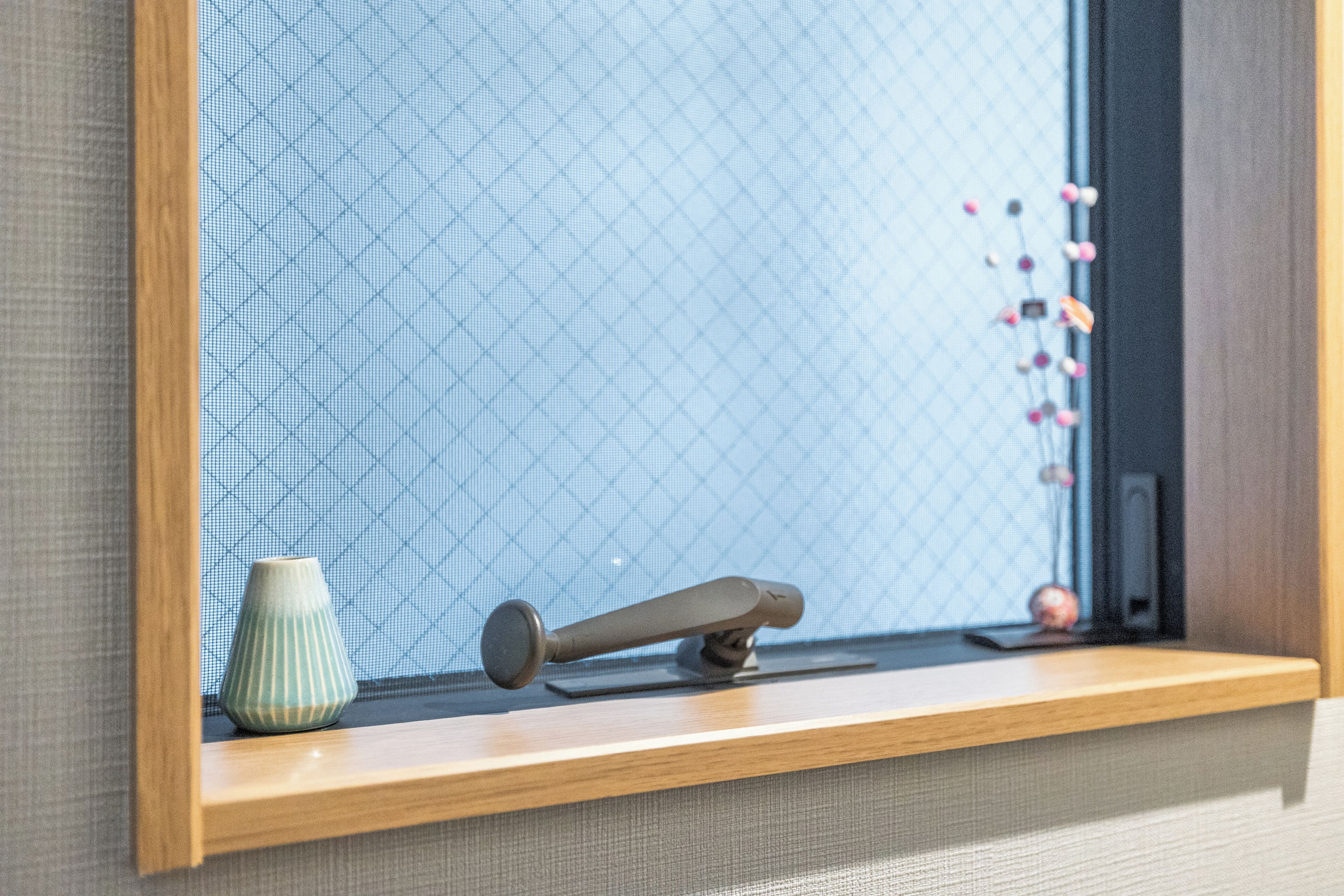 A wooden shelf with a small vase and a black object.