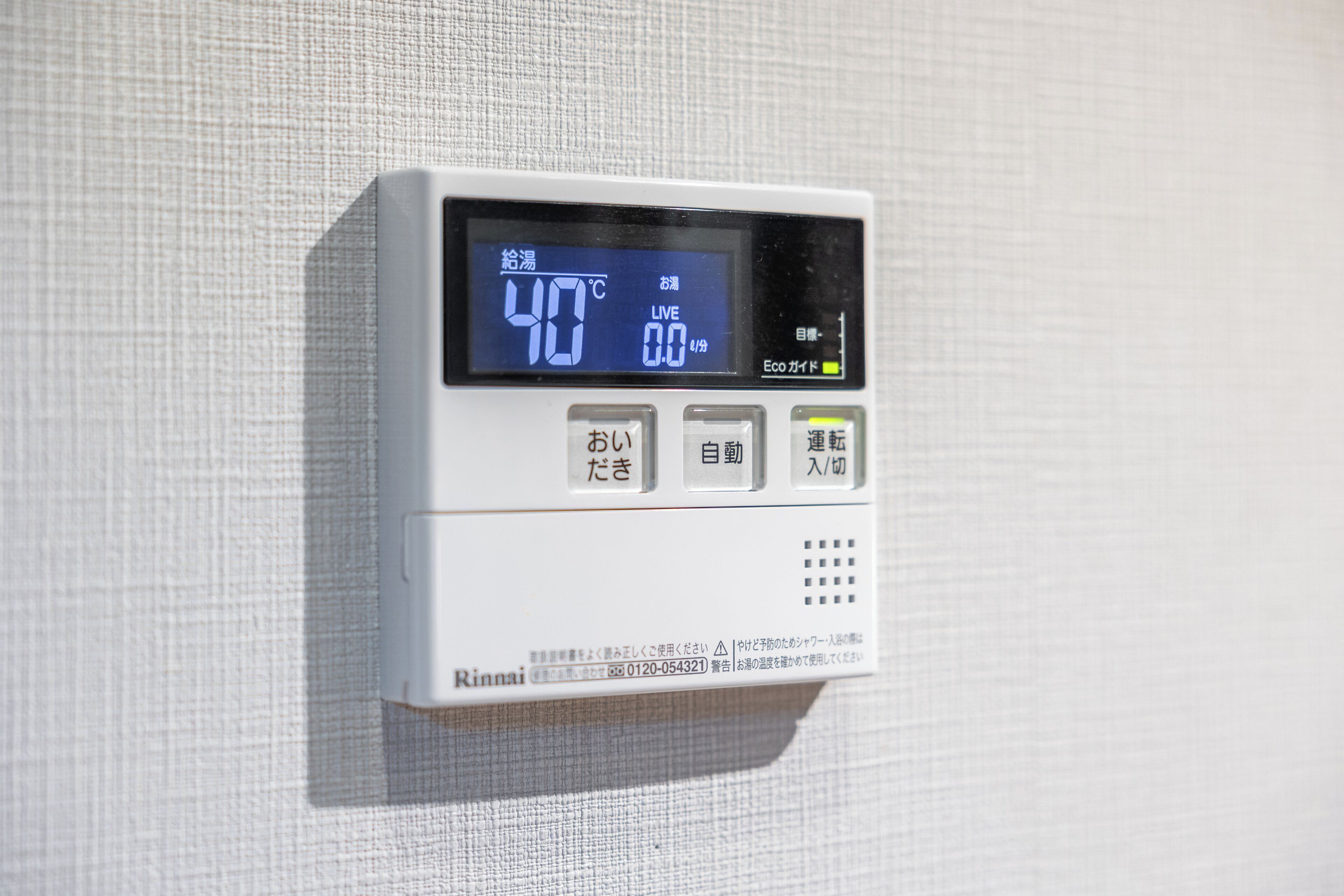 A digital thermostat mounted on a textured wall displaying a temperature of 40°C.