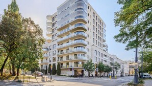 Un hôtel à plusieurs étages doté de balcons, d’un passage piéton et d’arbres.