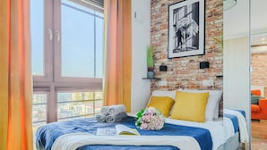 Une chambre d’hôtel moderne avec un grand lit, un mur en briques et une vue sur la ville.
