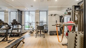 Une salle de sport équipée de tapis de course, d’appareils de musculation et d’un rameur.