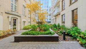Une cour intérieure avec un jardinière centrale, entourée d’immeubles dotés de balcons et de fenêtres.