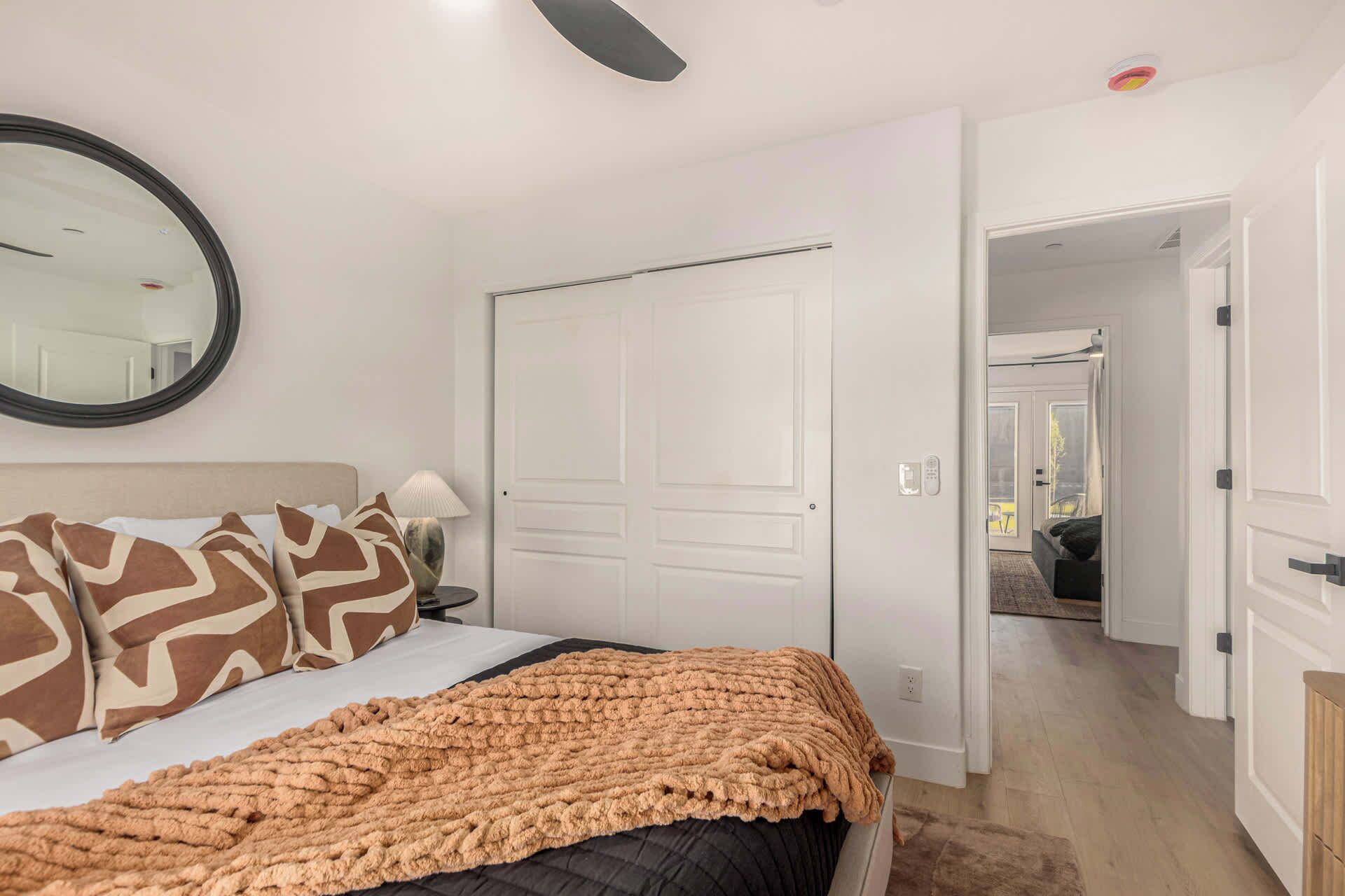Ein Schlafzimmer mit Bett, Spiegel, Tür und einem Flur, der in einen anderen Raum führt.