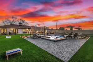 Un patio trasero con piscina, sillones de descanso y un área de estar techada.