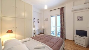 A bedroom with a bed, wardrobe, TV, and a balcony with curtains. - Your perfect choice for stay in Athens (Athina)