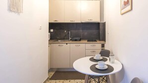A compact kitchen with a sink, cabinets, and a small dining table with cups. - Your perfect choice for stay in Athens (Athina)