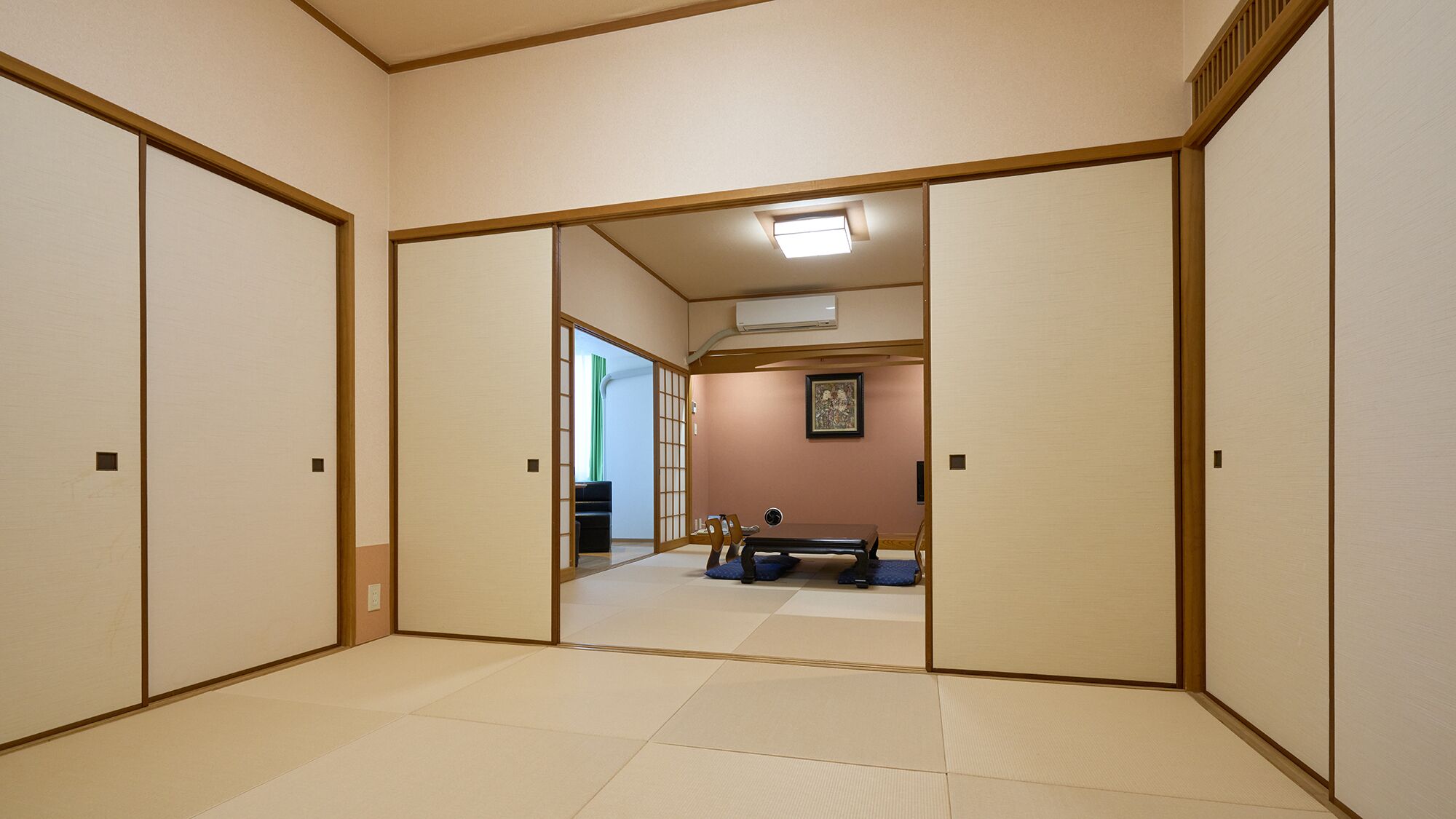 A traditional Japanese room with tatami flooring, sliding doors, and a ceiling fan.