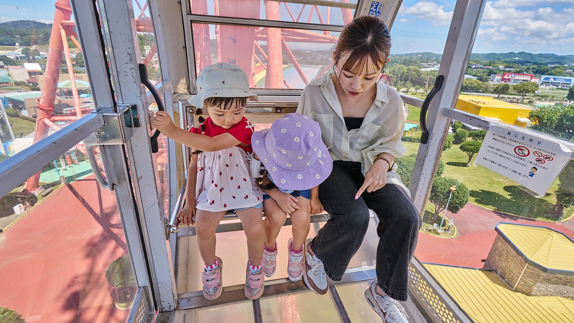 Eine Frau und ein Kind befinden sich in einem gläsernen Aufzug mit Blick auf eine Achterbahn und die Landschaft.