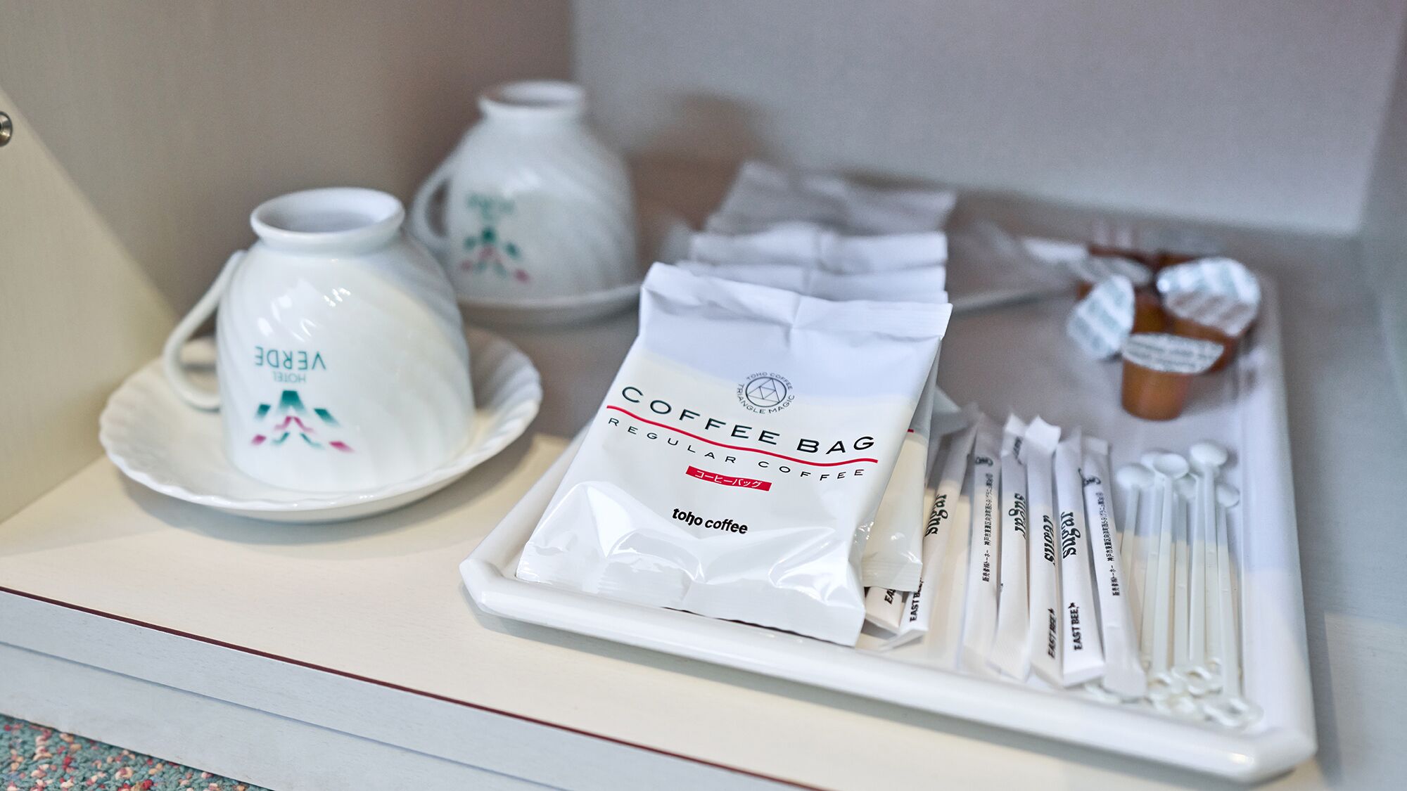A coffee station with a coffee bag, tea bags, and teapots.