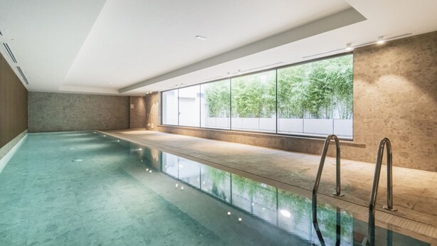 An indoor swimming pool with clear glass walls, a view of greenery outside, and a modern design. - Easylife - Apartment with Terrace and Comfort (Milano)