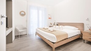 A modern bedroom with a wooden bed, a white chair, and a desk. - Easylife - Apartment with Terrace and Comfort (Milano)