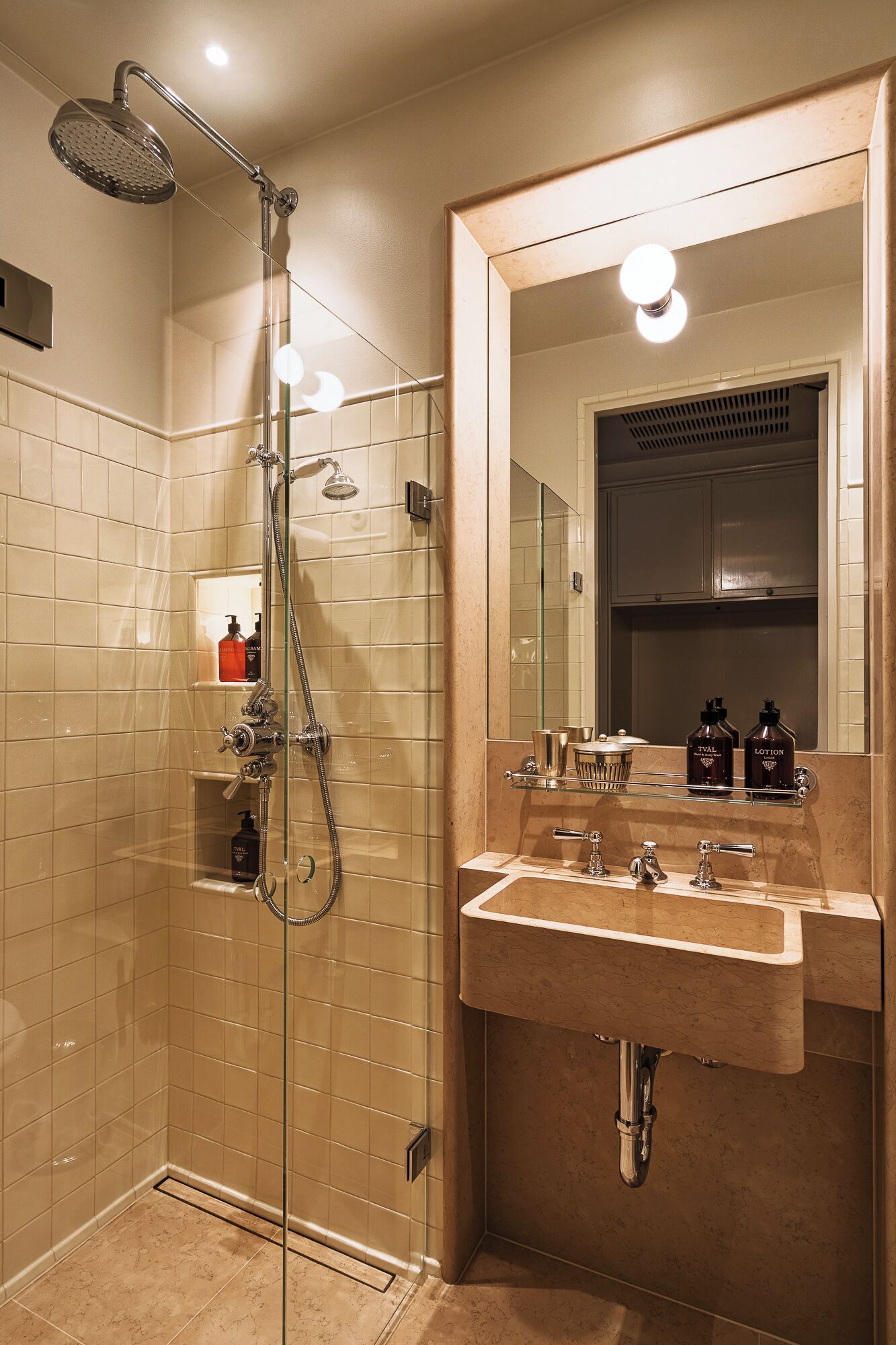 A modern bathroom with a glass-enclosed shower, a large mirror, and a vanity with a sink.