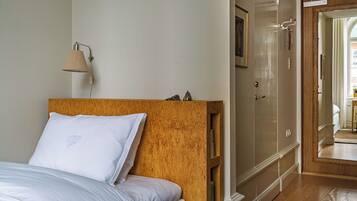 Une chambre à coucher avec une tête de lit en bois, un lit avec une literie blanche, une lampe de chevet, une armoire et un miroir.