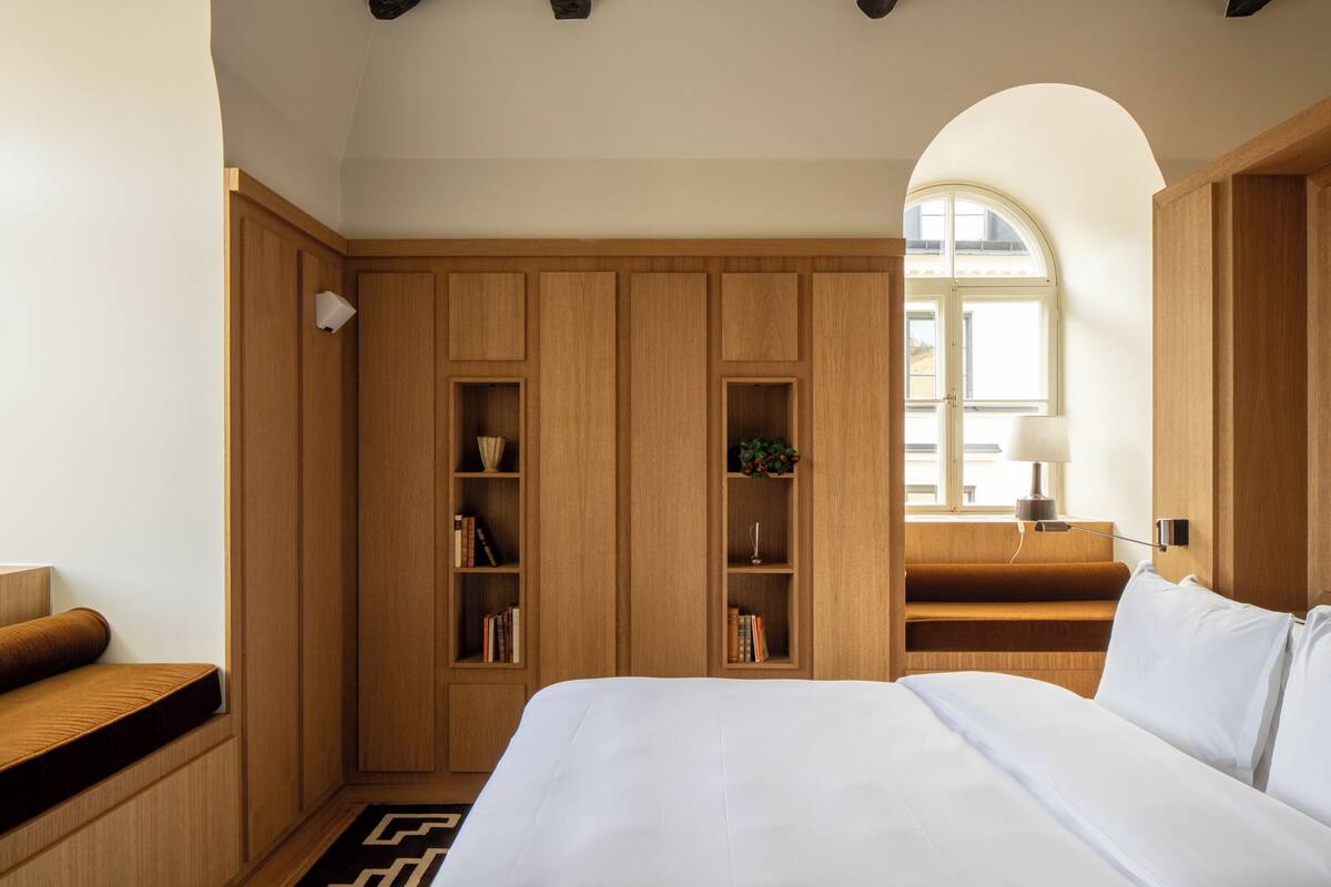 Un dormitorio con una cama grande, armario de madera, estanterías empotradas y una ventana con luz natural.