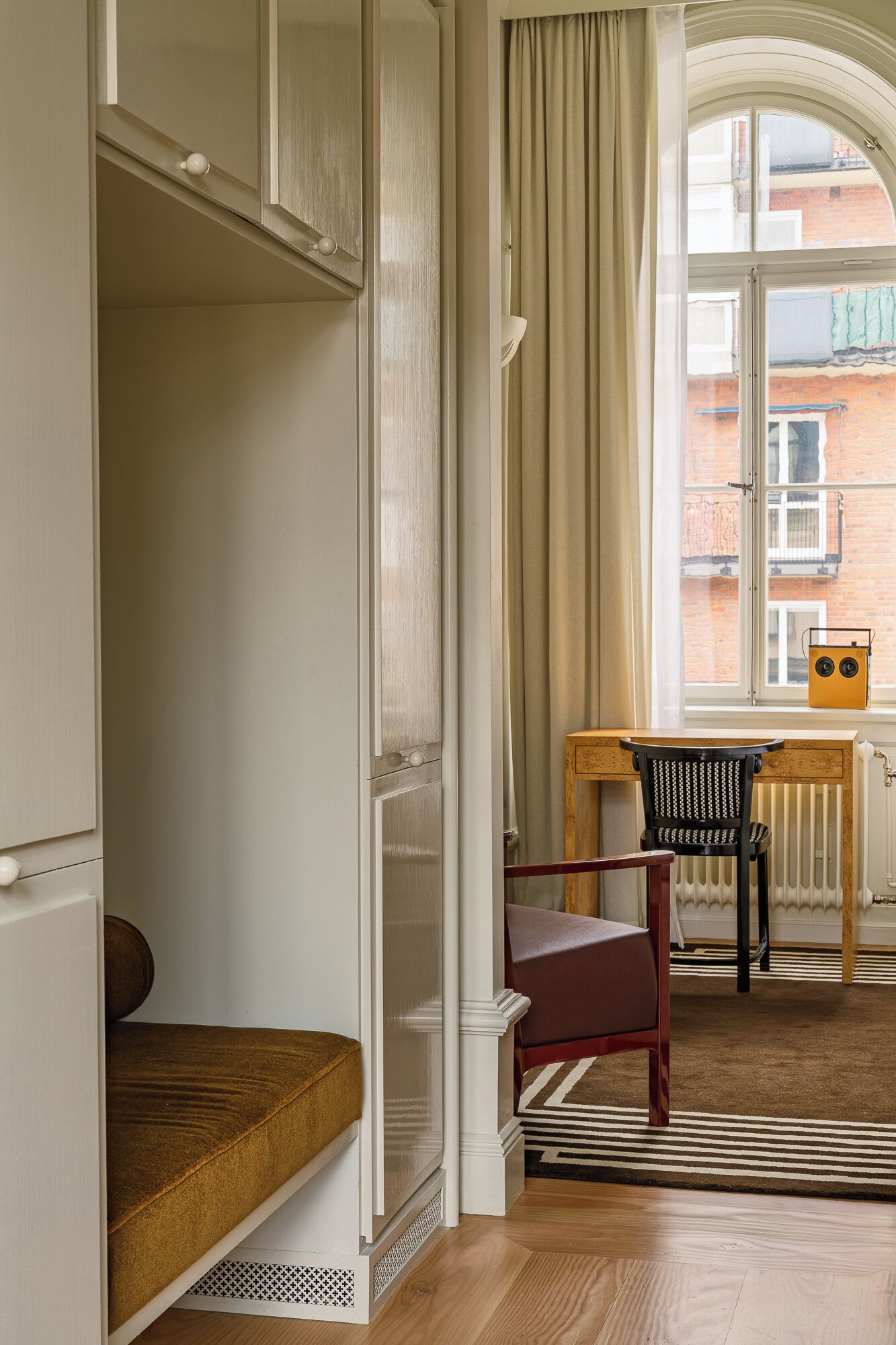 A room with a wooden bench, a chair, a table, and a radiator.