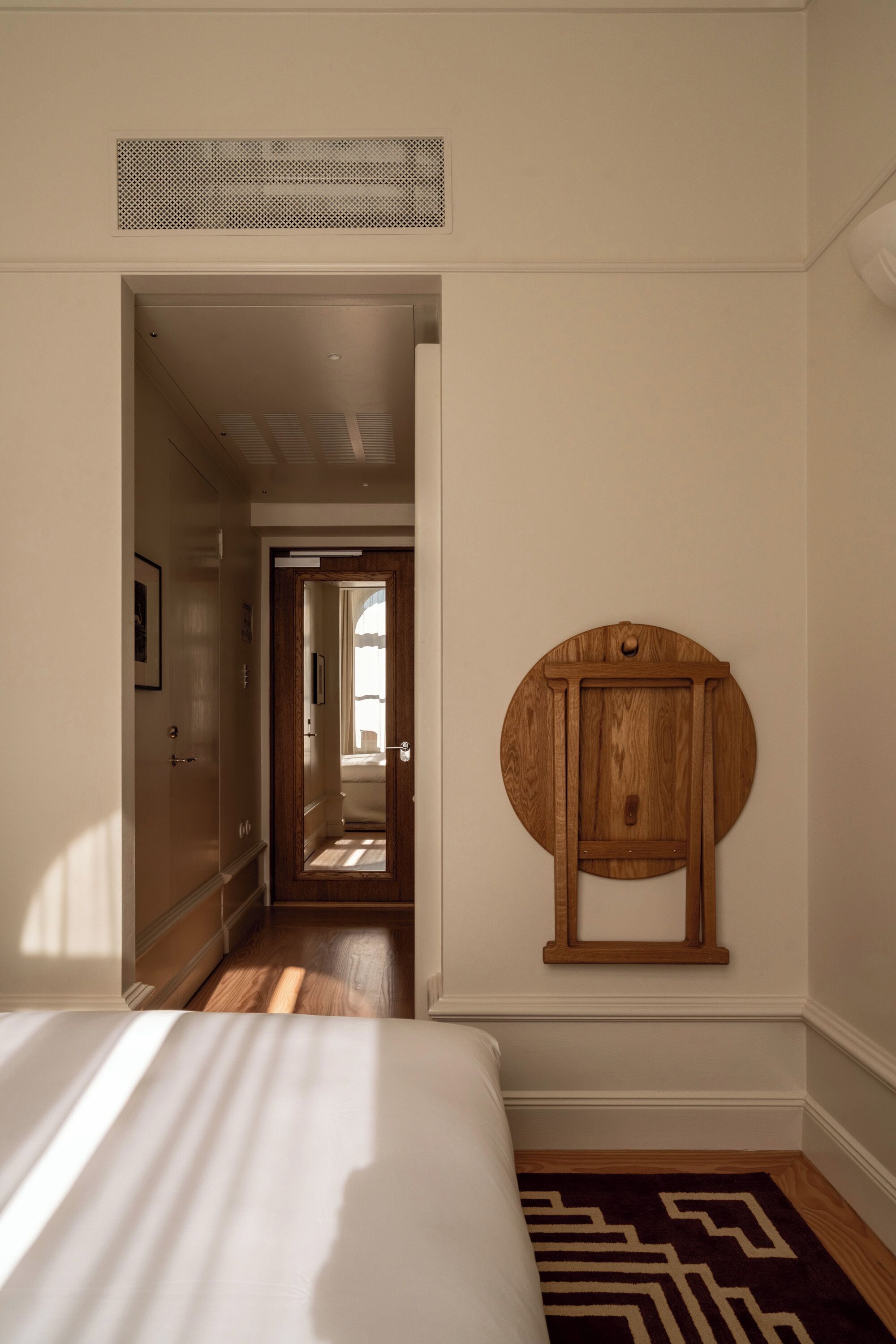 A bedroom with a bed, a wooden cabinet, and a hallway leading to another room.