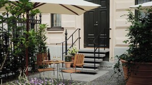Un patio con mobiliario exterior, una escalera y plantas en macetas.