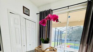 Un coin repas avec une table en marbre noir, un vase blanc et une chaise en osier.
