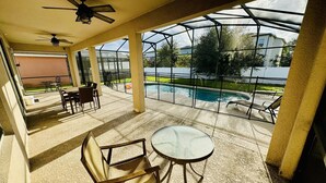 Un espace extérieur abrité comprenant une piscine, des chaises et une table.