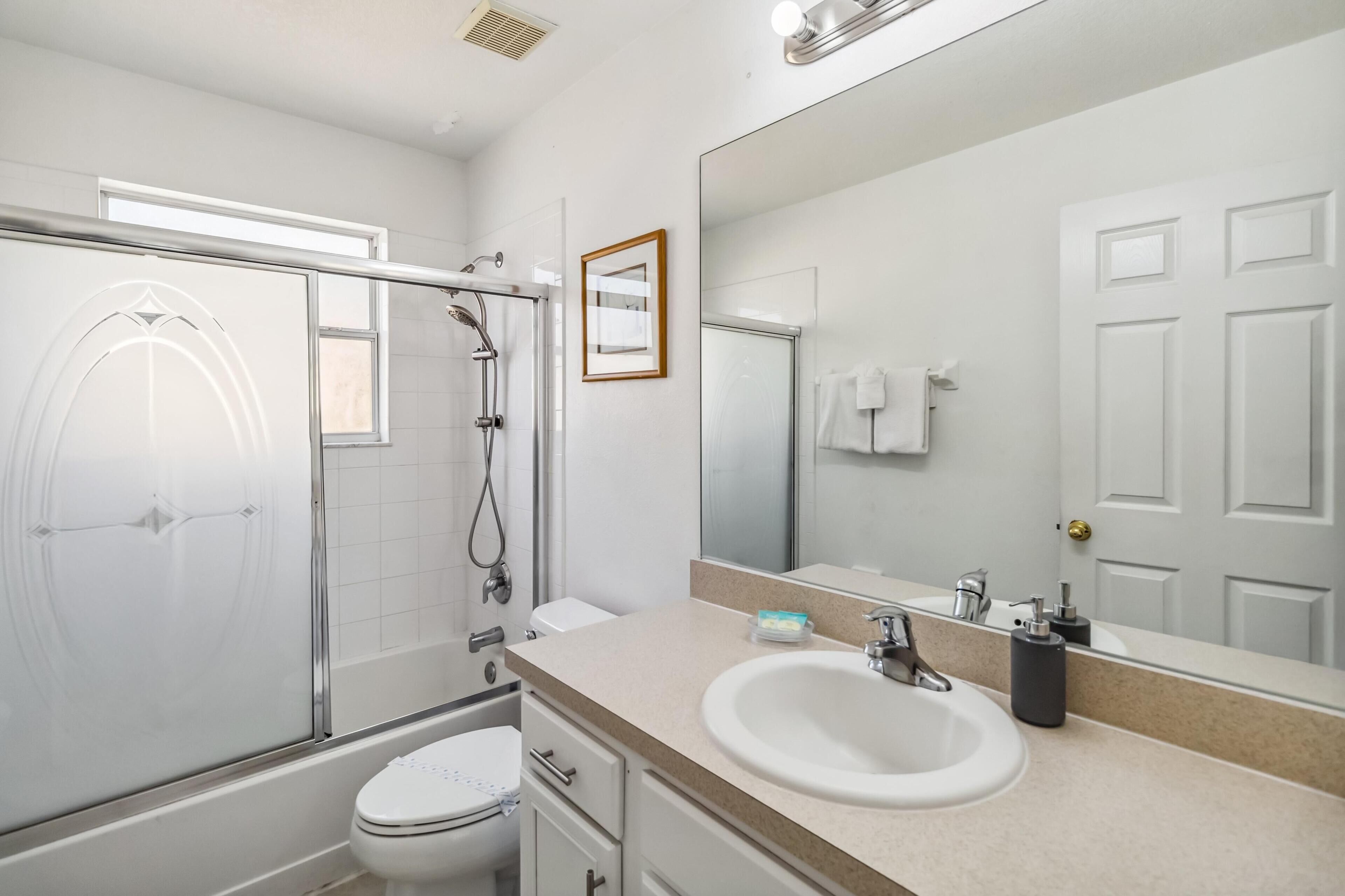 A modern bathroom with a glass shower enclosure, a white toilet, a sink with a mirror, and a towel rack.
