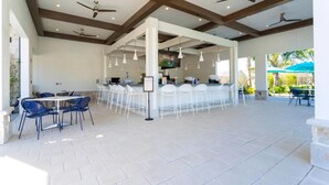 A spacious outdoor area with a bar, seating, ceiling fans, and a tiled floor. - Storey Lake Resort, Private Pool, Near Famous Attractions!! (Kissimmee)