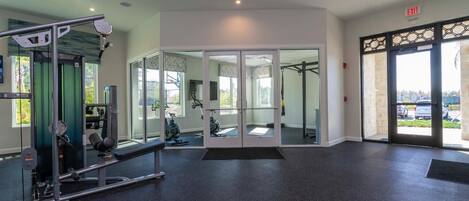 A gym with exercise equipment, a large mirror, and a glass door leading outside.