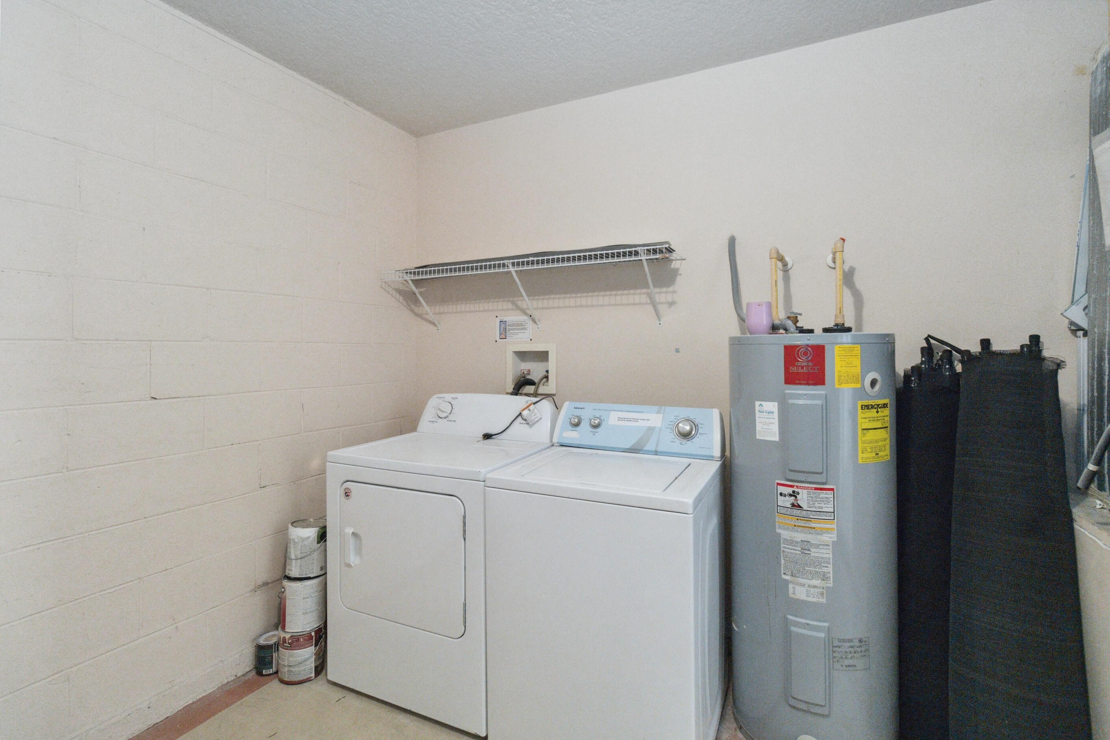 A laundry room with a front-loading washer and dryer, a utility sink, and a water heater.