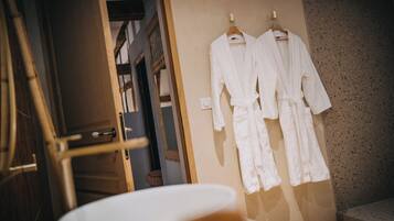Une salle de bain avec un lavabo et deux peignoirs blancs accrochés au mur.