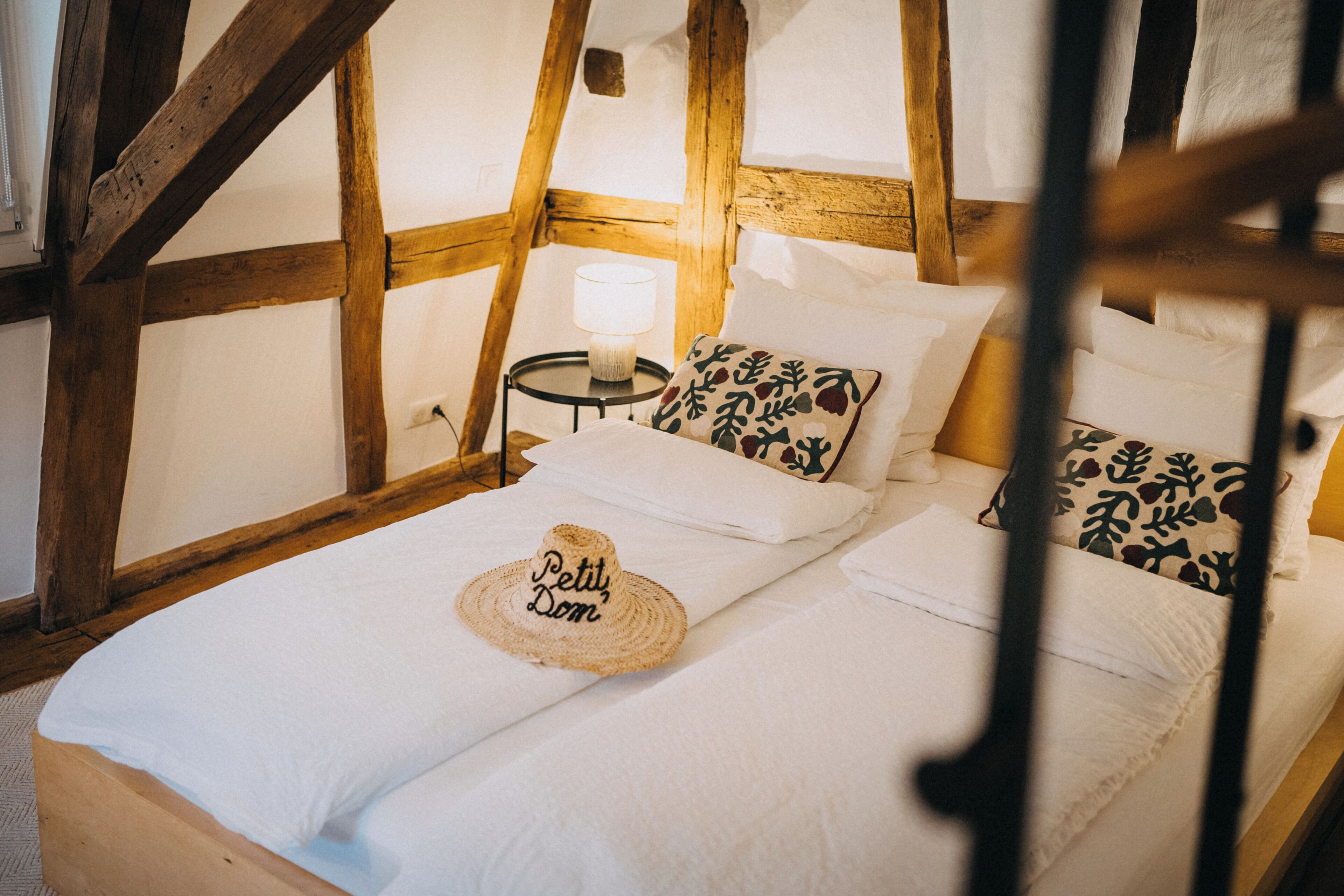A cozy room with a bed, a nightstand, and a lamp.