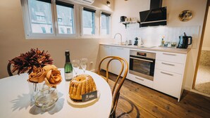 Een moderne keuken met witte kasten, een houten plafond en een eethoek met een tafel voor twee personen.