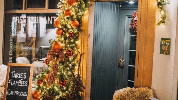 Een restaurant genaamd 'RESTAURANT PETIT DOMINIC' met feestelijke kerstdecoratie buiten.