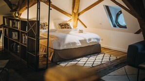 Een gezellig slaapkamer onder de dakpannen met een bed, een boekenkast en een dakraam.
