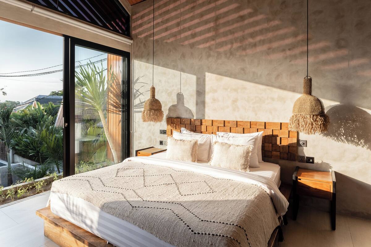 Een moderne slaapkamer met een groot bed, houten hoofdbord en hanglampen.