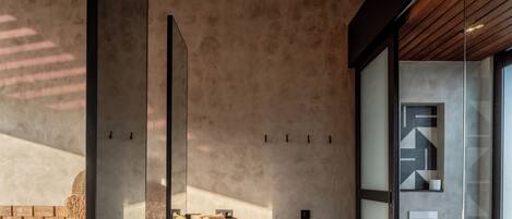 Un baño moderno con diseño minimalista, que cuenta con techo de madera, cabina de ducha de vidrio y un inodoro a la vista.