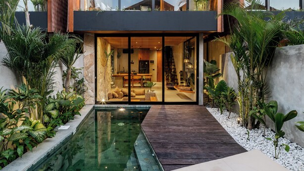 Una casa moderna de dos pisos con piscina, ventanas amplias y terraza de madera.